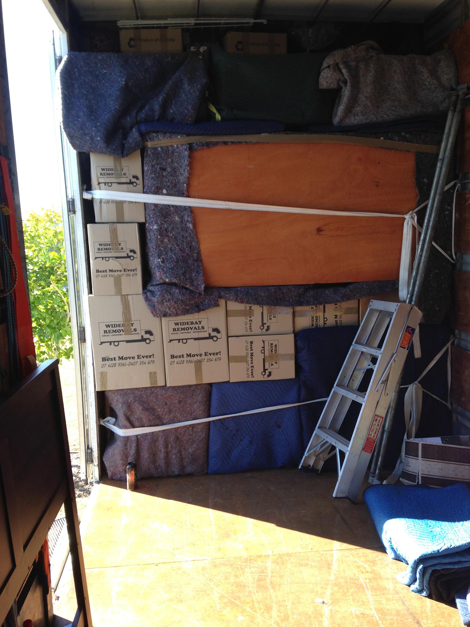 Inside a removals truck: boxes, padded furniture and a ladder strapped in place
