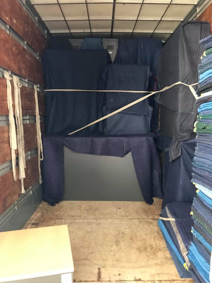 Blanket-wrapped furniture tied in place inside a removals truck