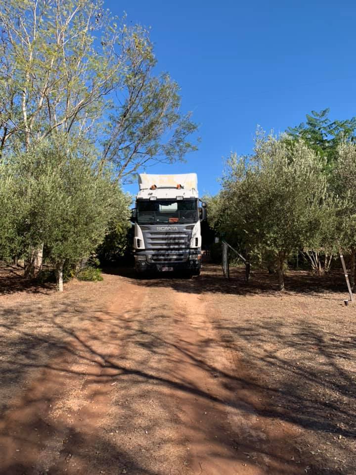 Removals truck on a red dirt track between rows of trees